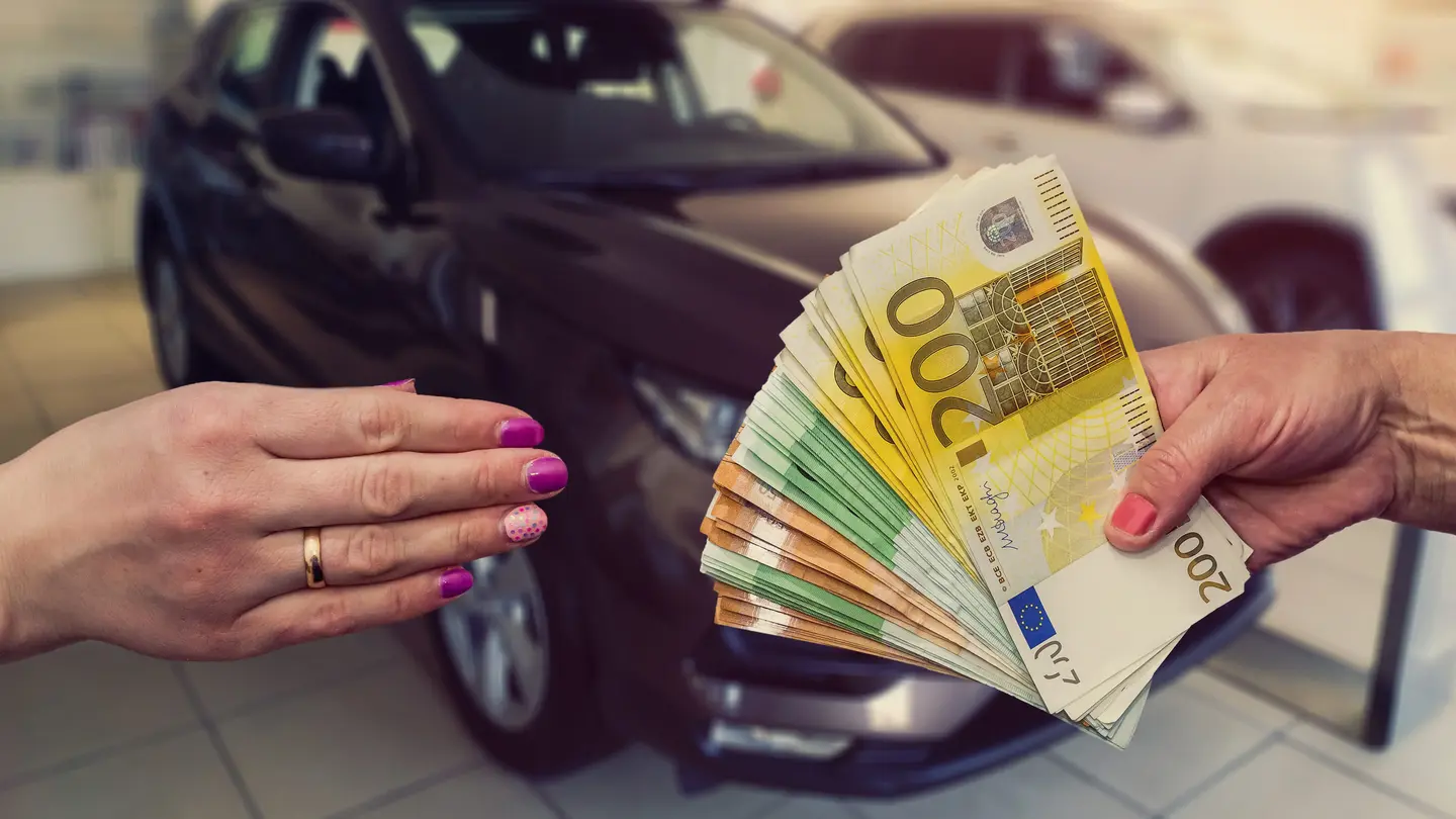 Autohändler übergibt Bargeld an Autoverkäufer